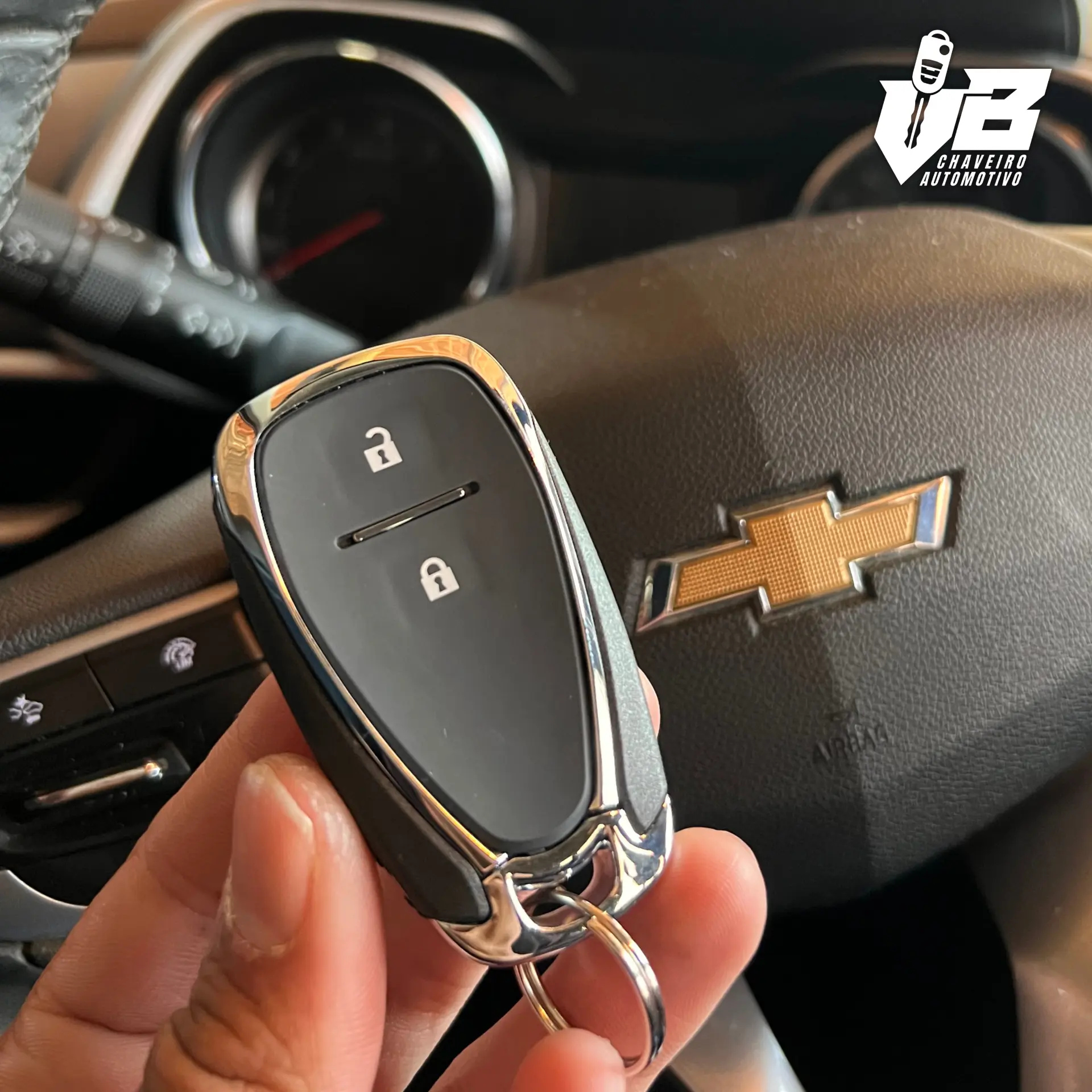 Mão segurando chave automotiva em frente ao volante de um veículo